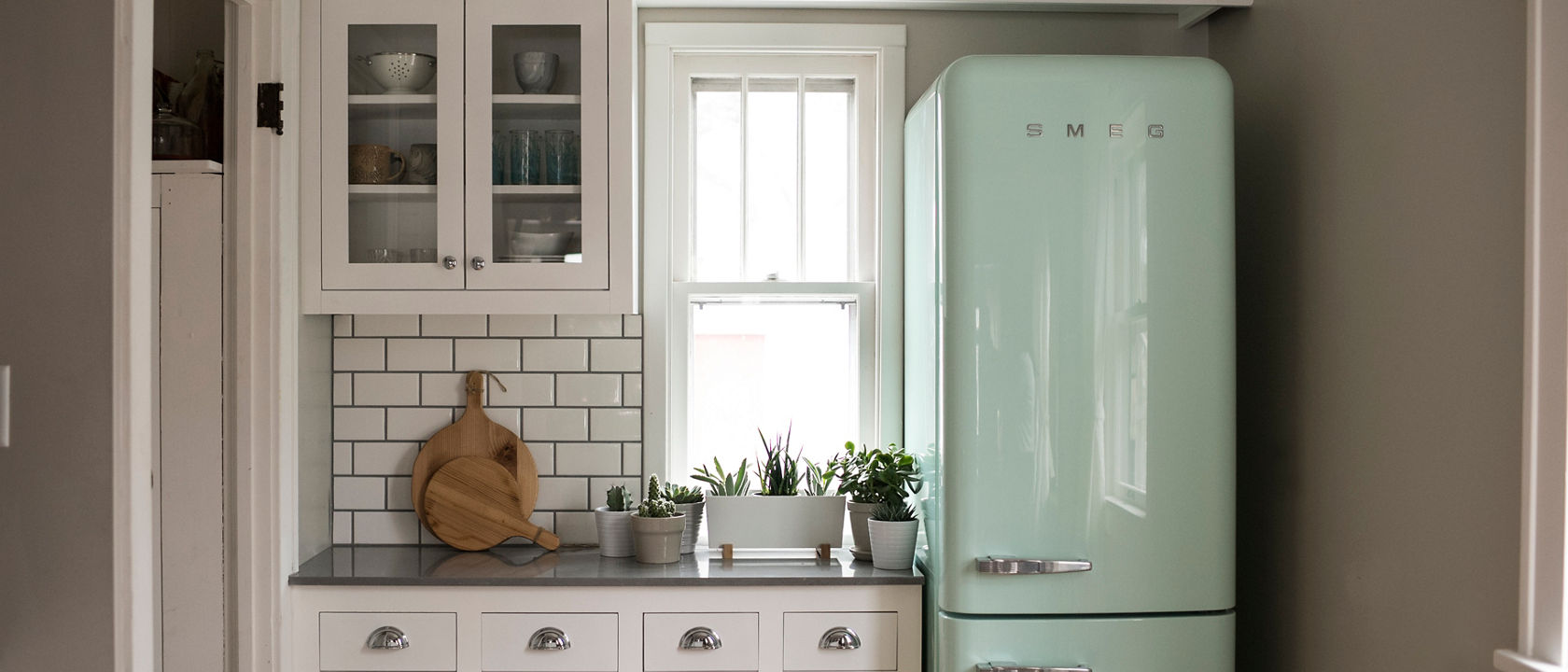 A galley kitchen with Carrick quartz countertops and a mint SMEG refrigerator