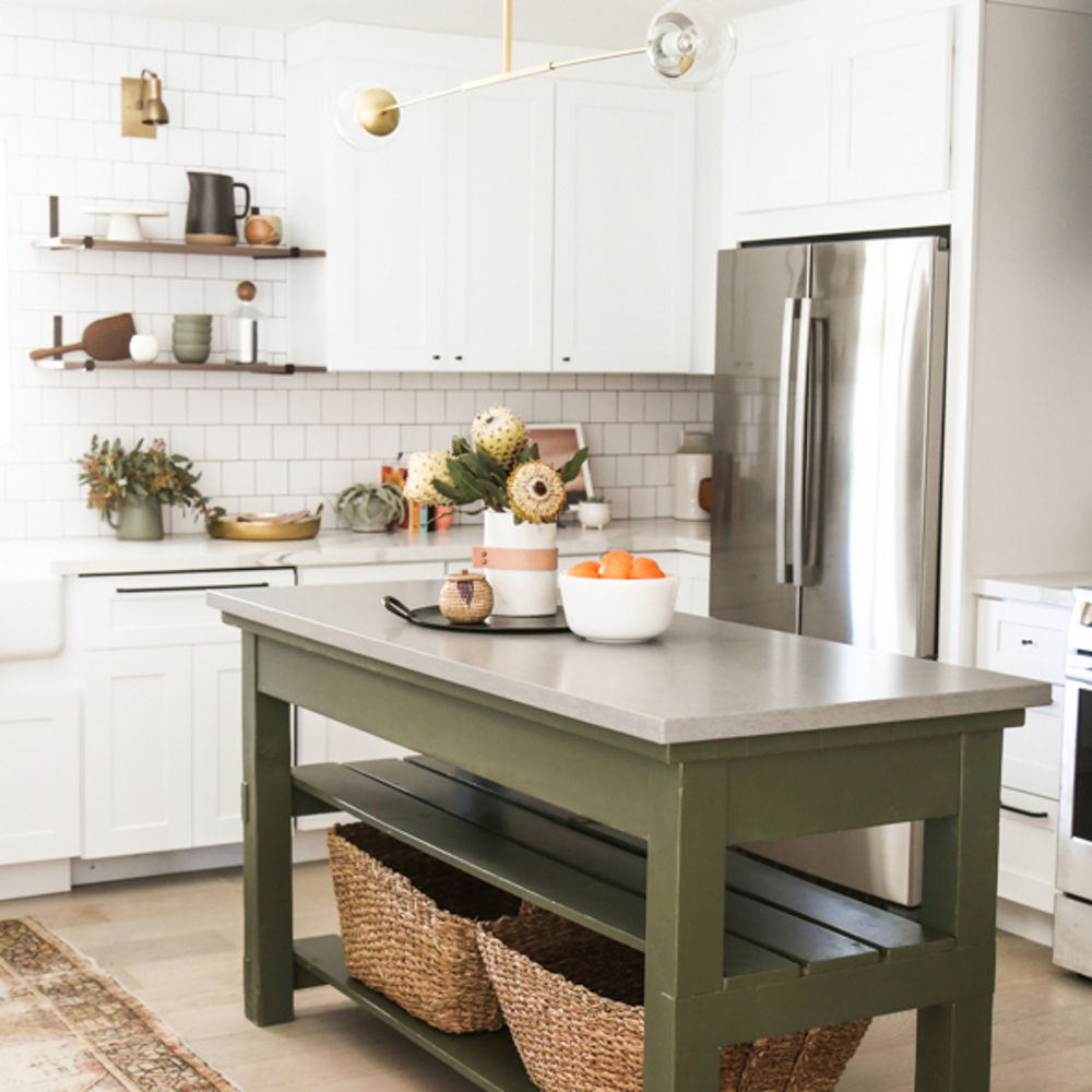 A vintage green kitchen with an island featuring white brick