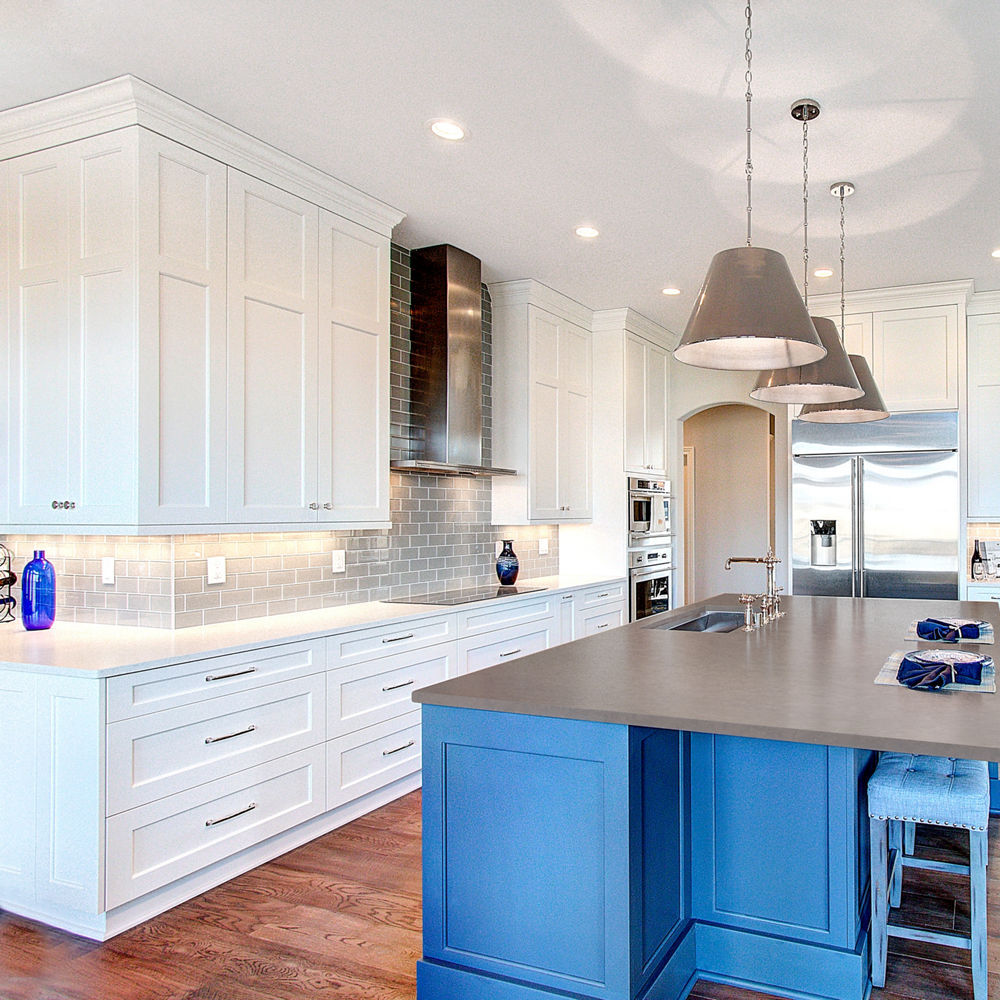 A beautifully sleek white and blue kitchen theme accessed by Cambria Carrick Matte and Swanbridge quartz countertops