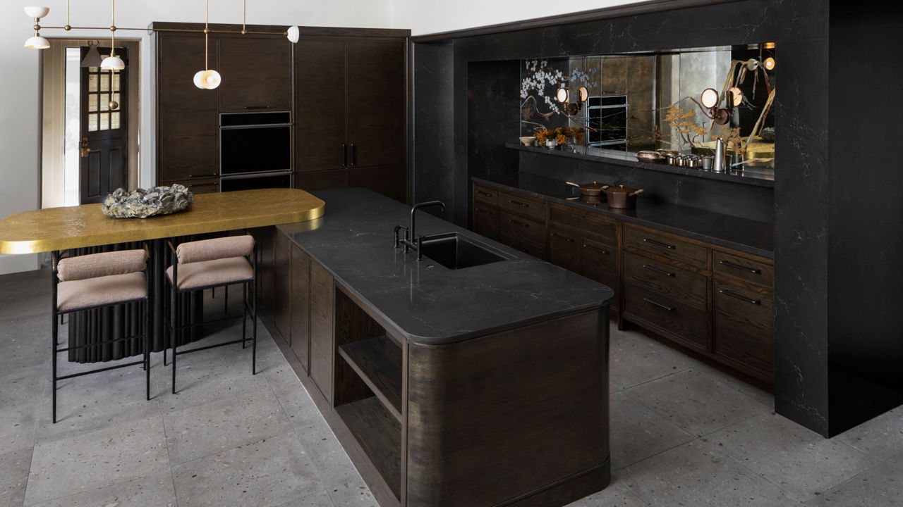 a sleek and modern kitchen with black cabinets, black quartz countertops, black appliances, and a mirror backsplash on one wall. 