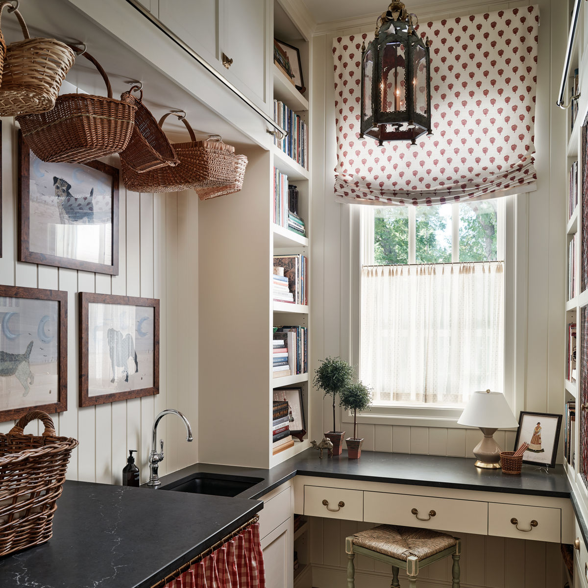a laundry room with a utility sink, desk and stool, black quartz countertops, and vintage decor.