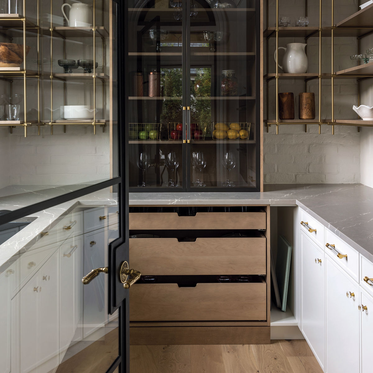 A pantry with maple and brass bistro-style shelves and Cambria Clare quartz countertops.