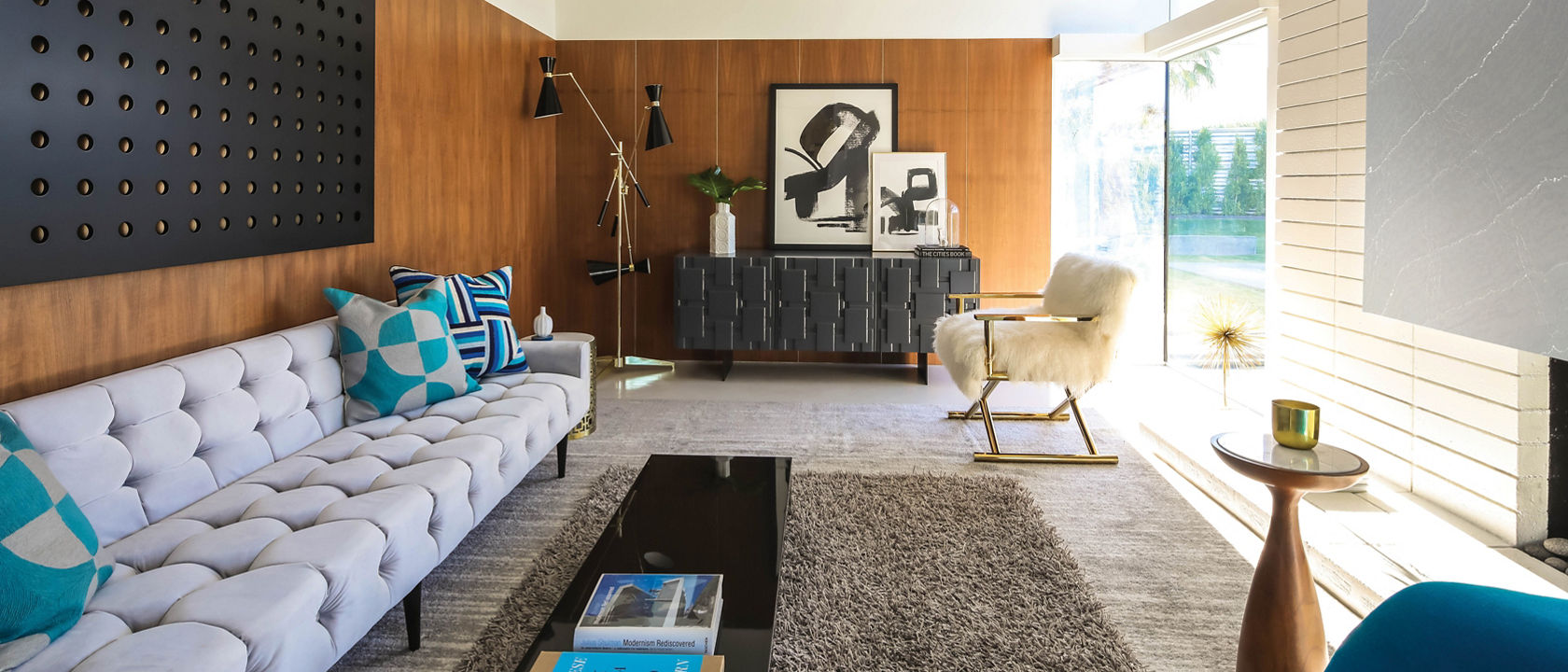 A mid-century modern living room with a white couch, shag carpet rug, wood paneling, and a gray quartz fireplace.