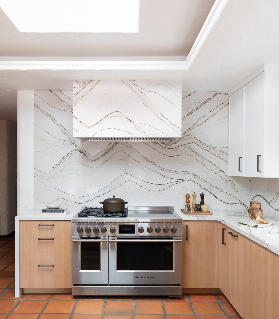 Kitchen with steel oven and stove surrounding a countertop and wall with Cambria Clovelly quartz.