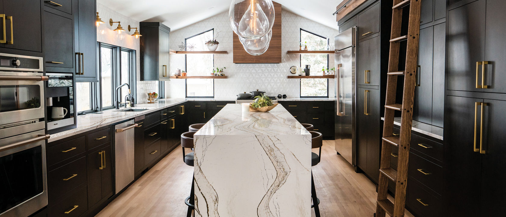 A modern farmhouse style kitchen with dark brown cabinets, a white tile backsplash, and a Clovelly quartz waterfall island 
