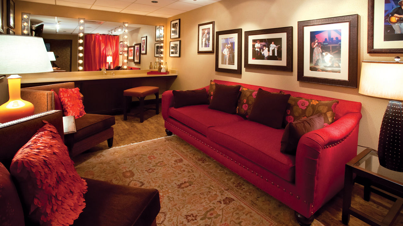 A Grand Ole Opery dressing room featuring a red couch, two armchairs, and Cambria quartz vanity.