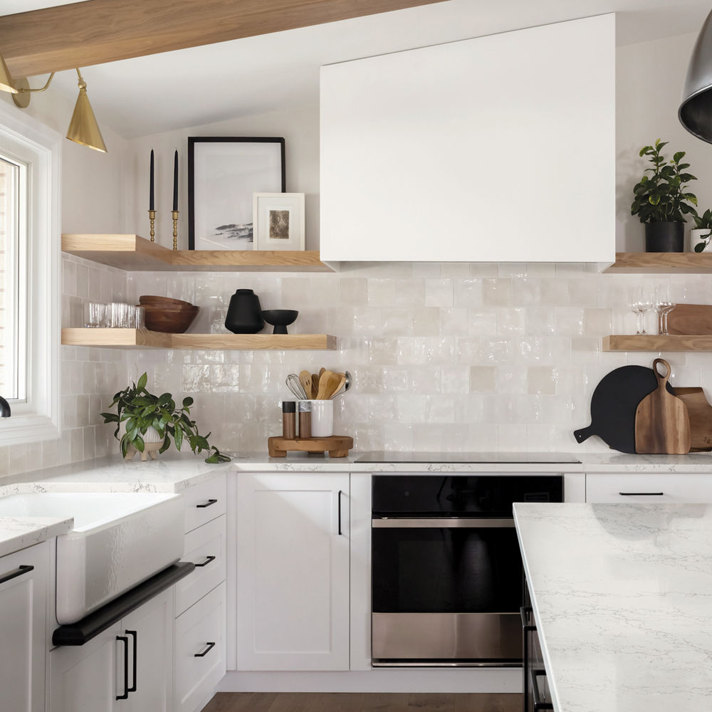 A clean, white kitchen with Colton quartz countertops, vaulted ceiling with wooden beams, white tile backsplash, and black accents throughout the space