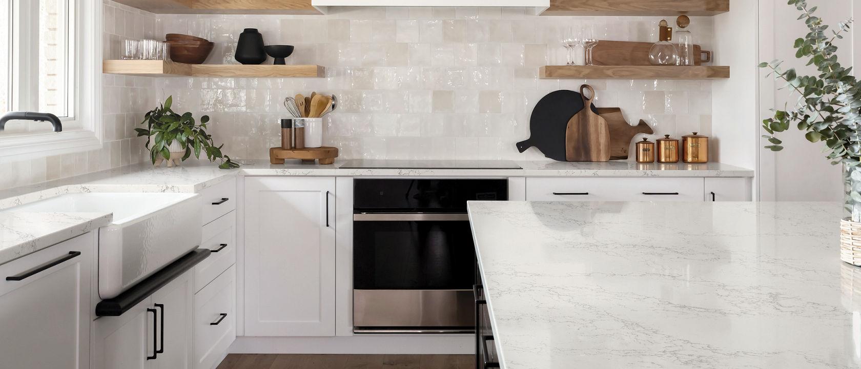 A clean, white kitchen with Colton quartz countertops, vaulted ceiling with wooden beams, white tile backsplash, and black accents throughout the space