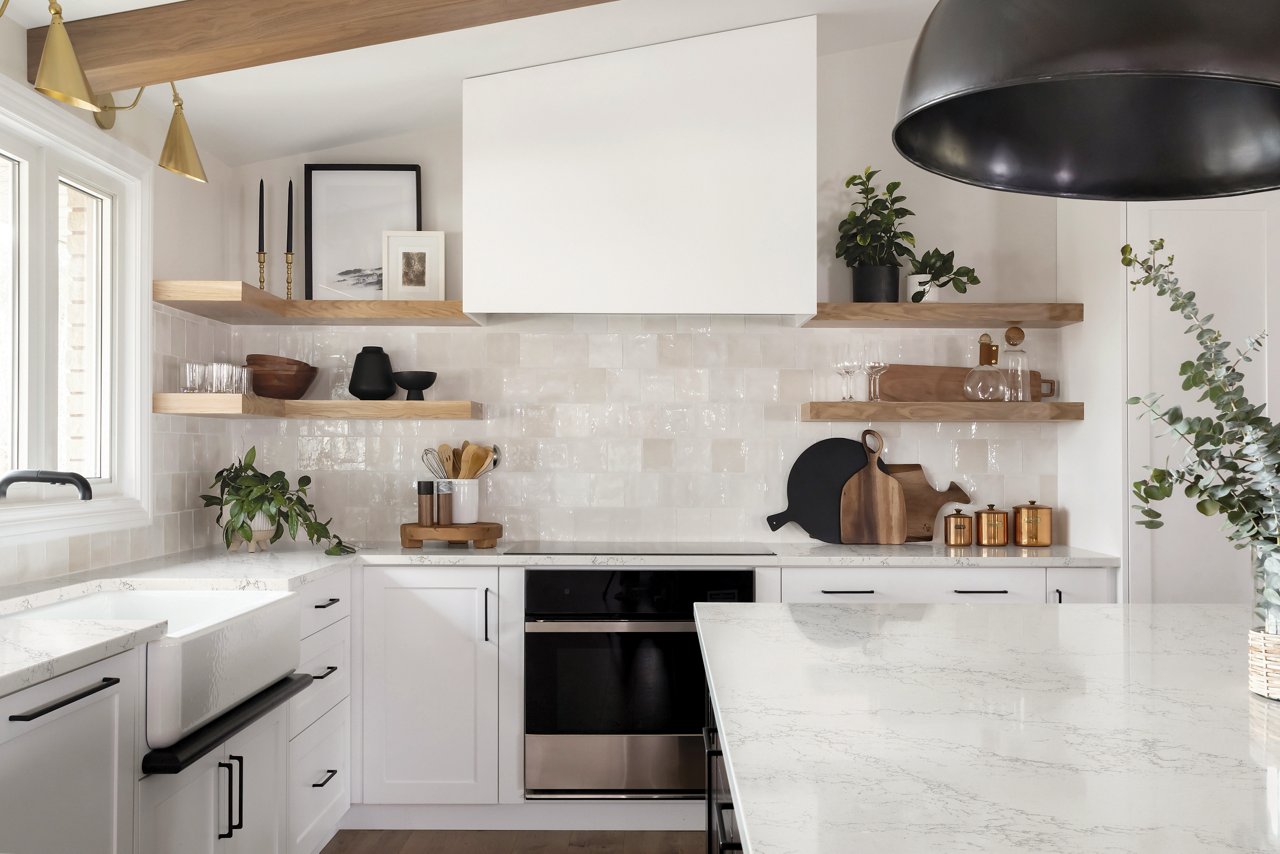 A clean, white kitchen with Colton quartz countertops, vaulted ceiling with wooden beams, white tile backsplash, and black accents throughout the space