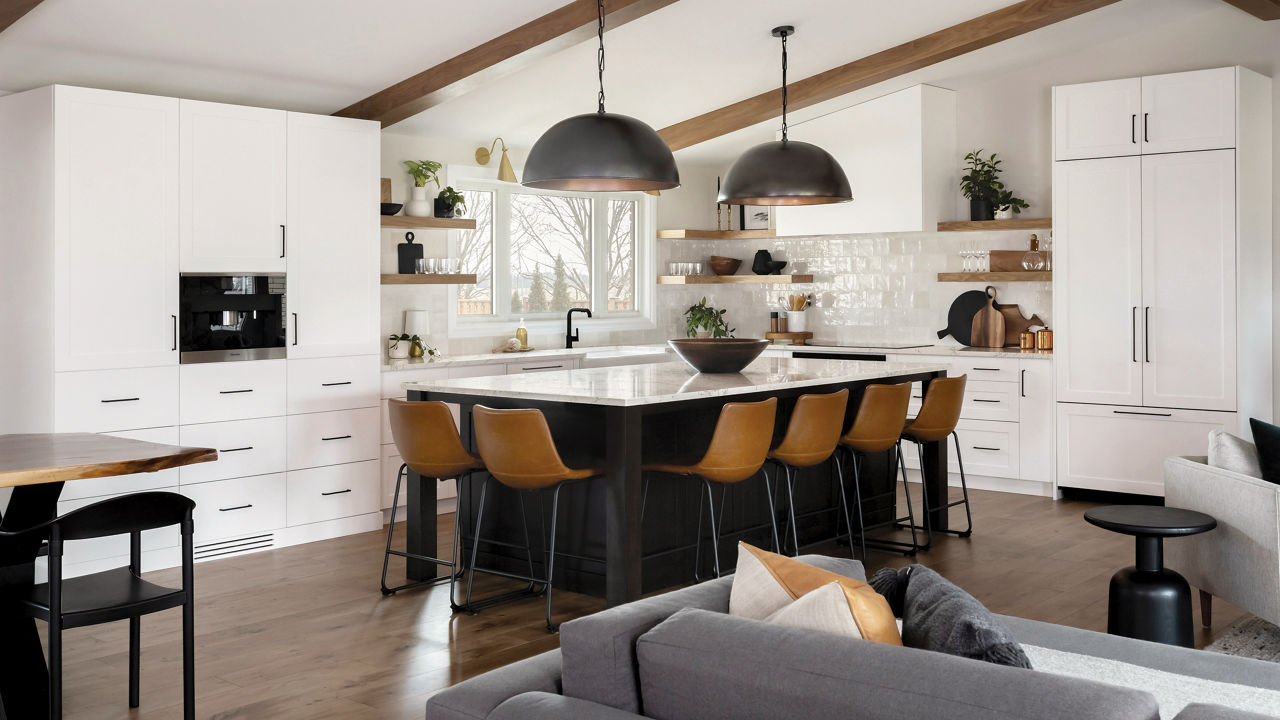 A kitchen with open wood shelving, vaulted ceilings with wooden beams, white cabinets and gorgeous center island with wooden barstools topped with Colton quartz countertops