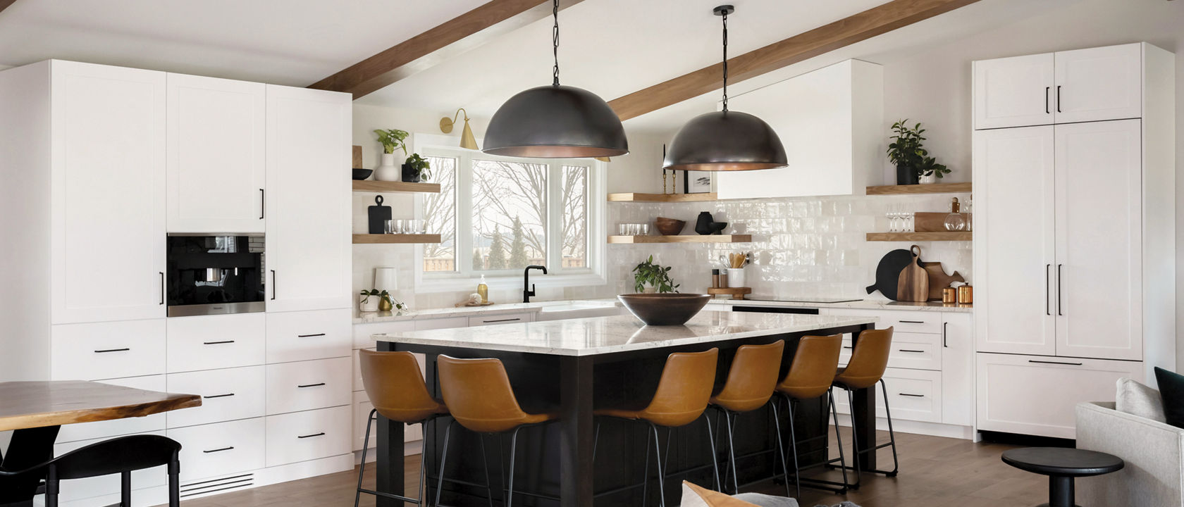 A kitchen with open wood shelving, vaulted ceilings with wooden beams, white cabinets and gorgeous center island with wooden barstools topped with Colton quartz countertops