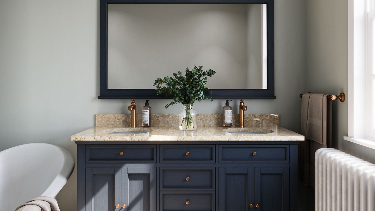 a bathroom with black cabinets, beige quartz countertops with two sinks, a rectangular black mirror with black trim, and an overhead wall light.