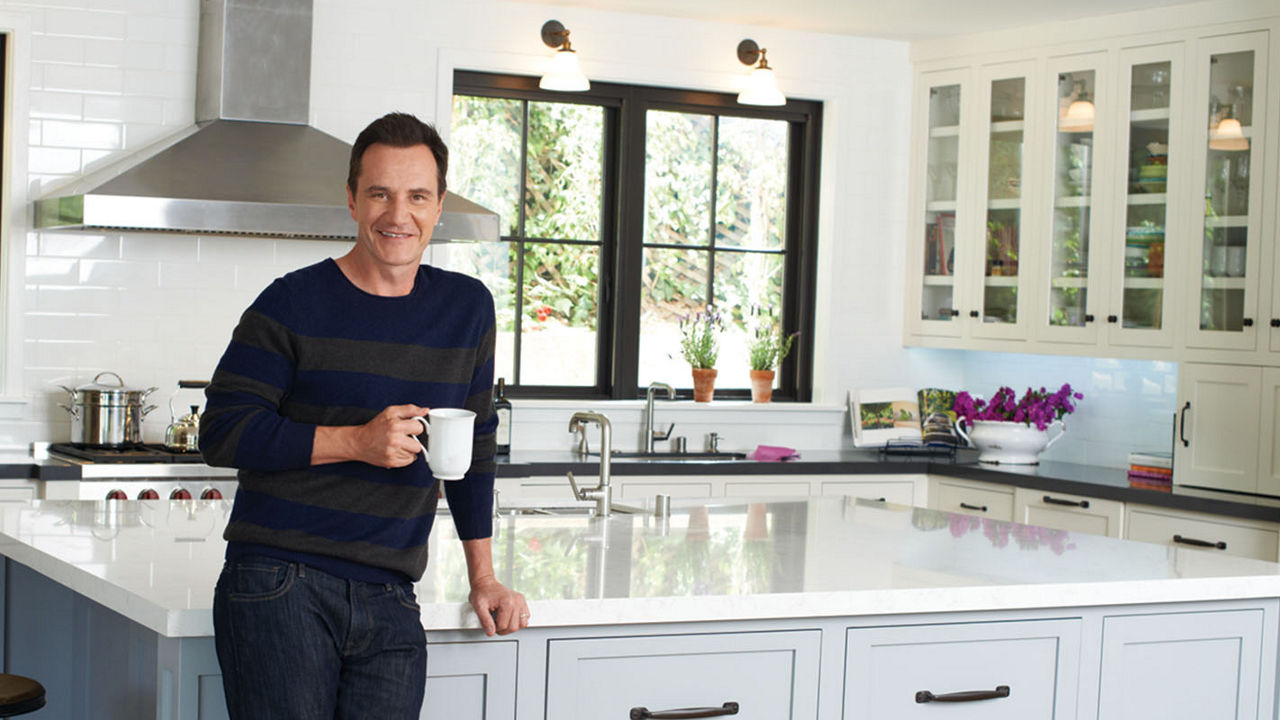 Tim DeKay posing in front of his kitchen featuring Cambria quartz countertops.
