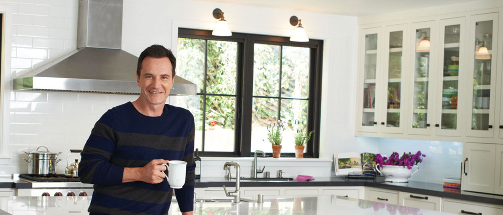 Tim DeKay posing in front of his kitchen featuring Cambria quartz countertops.