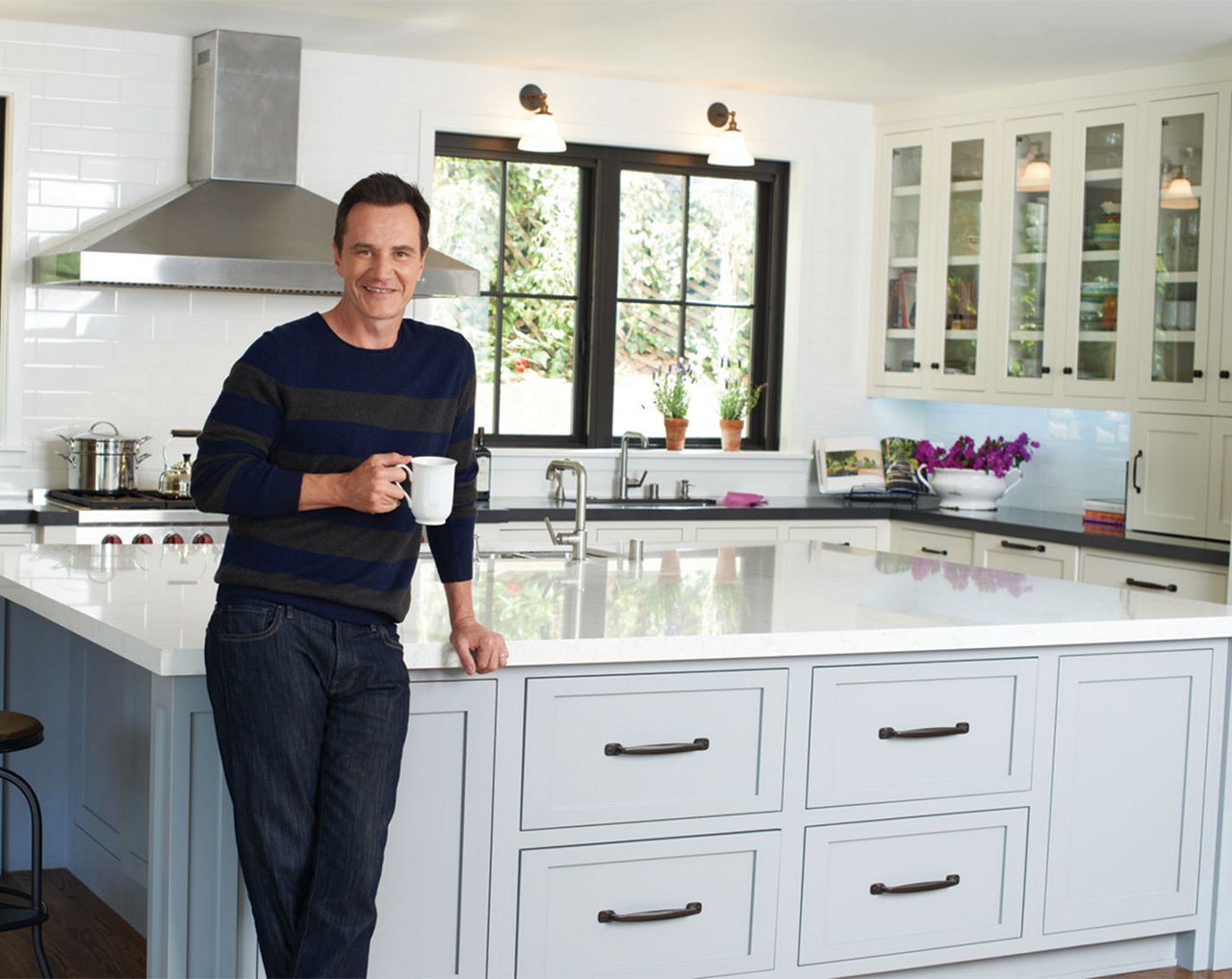 Tim DeKay posing in front of his kitchen featuring Cambria quartz countertops.