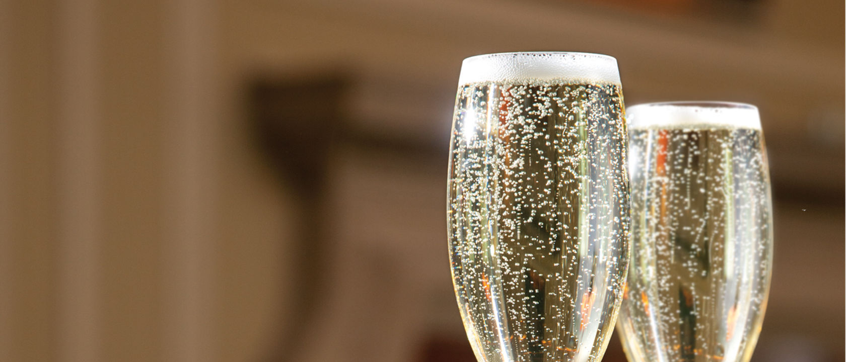 Two bubbling champagne glasses sitting on top of Cambria Langdonz™ quartz countertops.