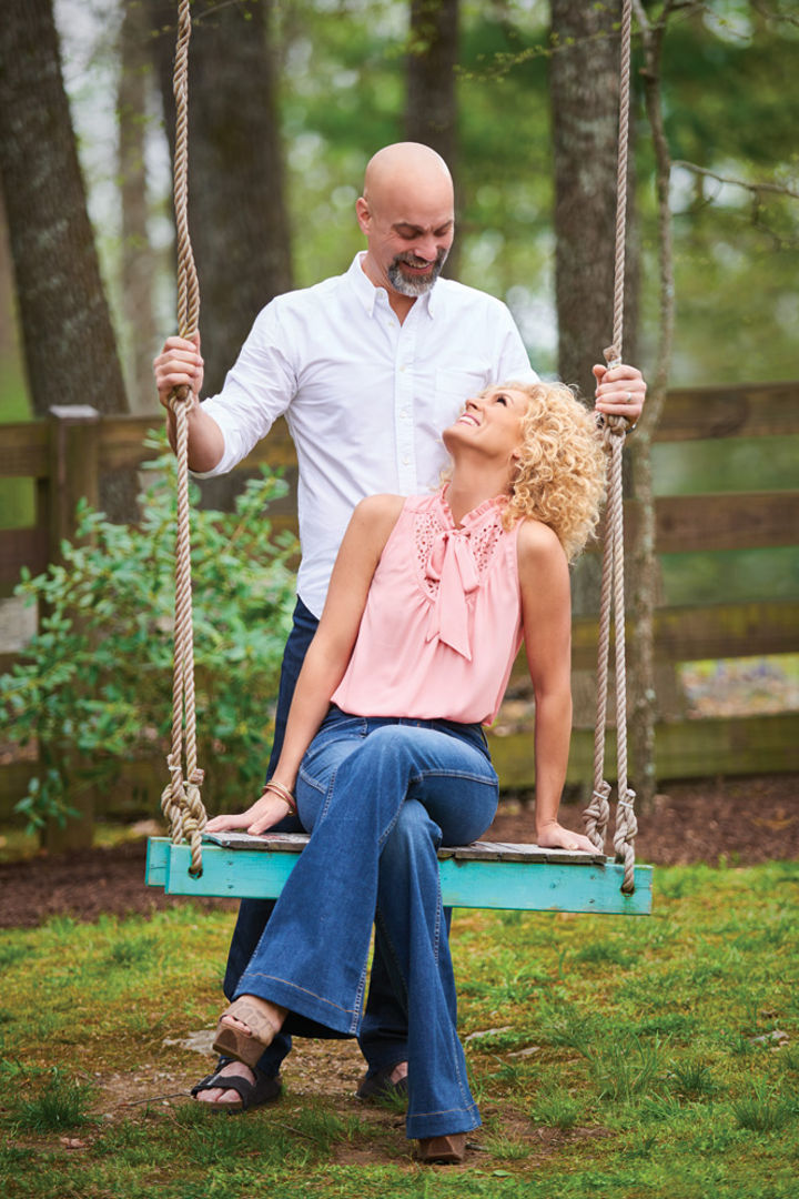 Photograph of Kimberly Schlapman sitting on a swing looking up at a man standing behind her.