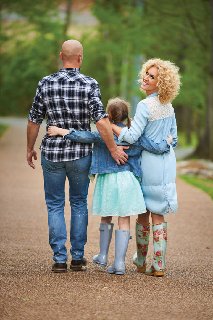 Photograph of Kimberly Schlapman looking back as she is walking down a road beside a man and young girl.