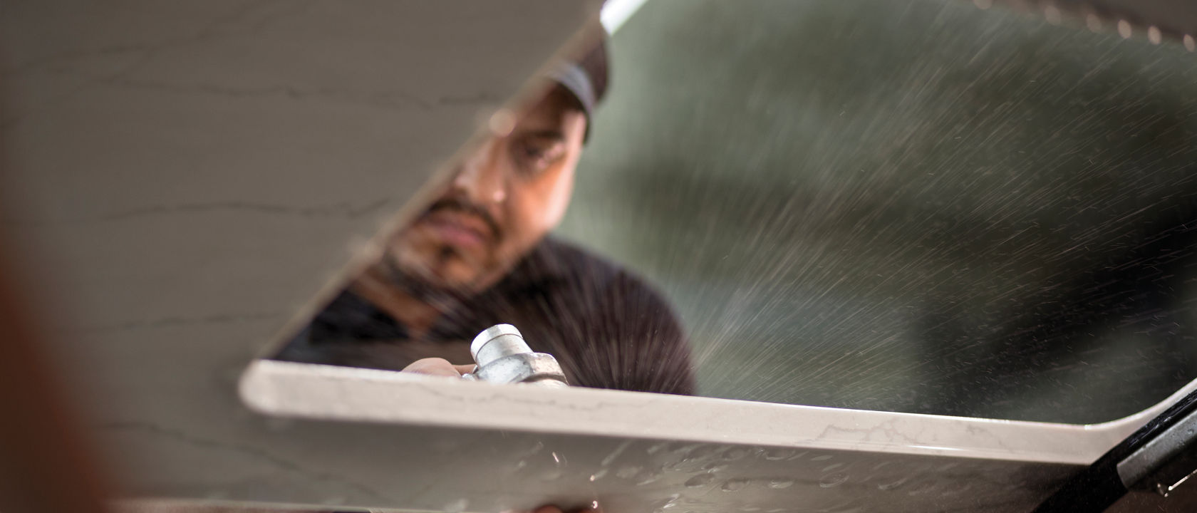 A Cambria worker polishing a slab of white quartz.