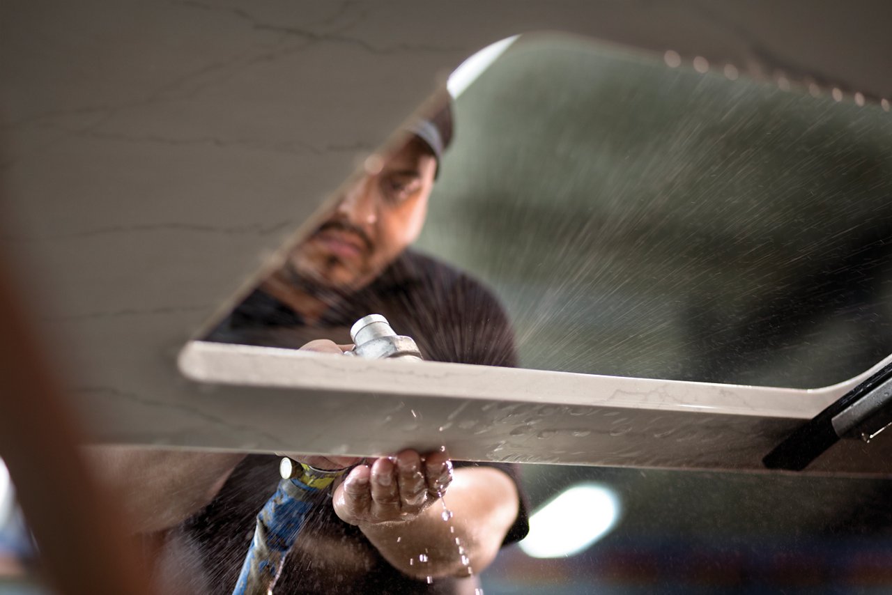 A Cambria worker polishing a slab of white quartz.