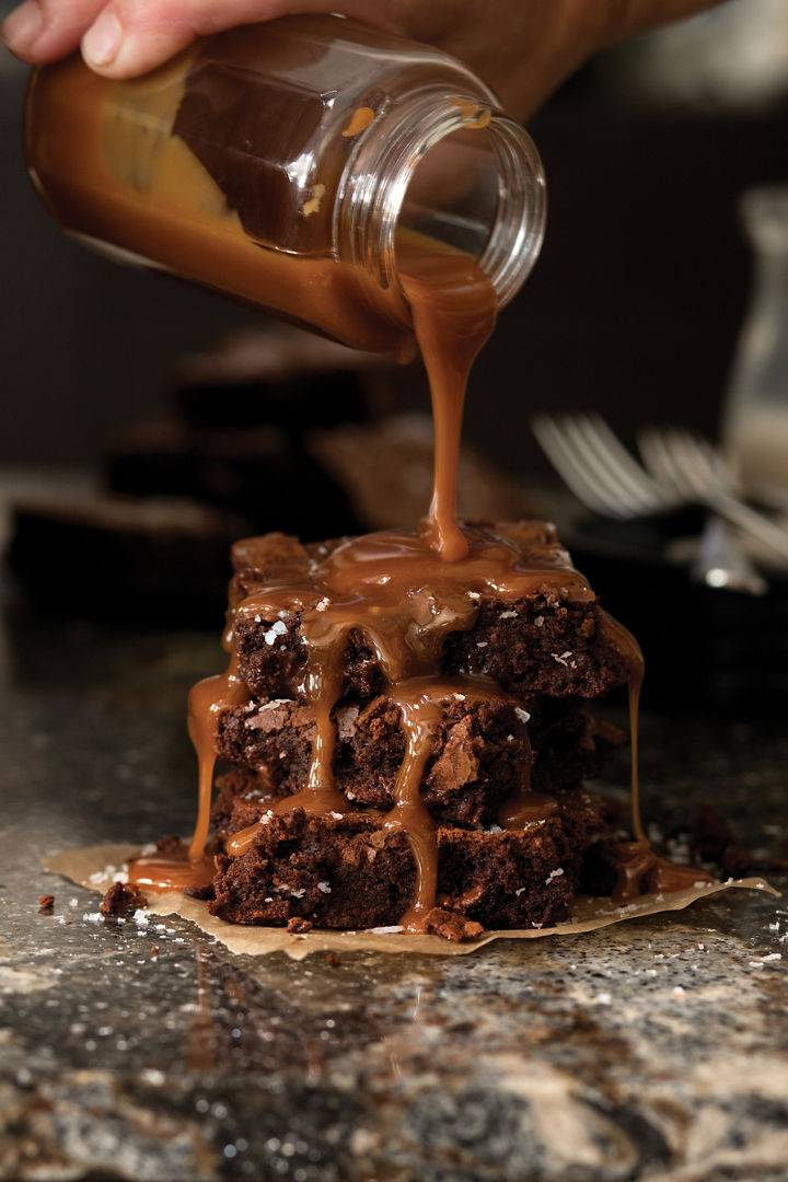 Salted caramel brownies sitting on top of black quartz countertops.