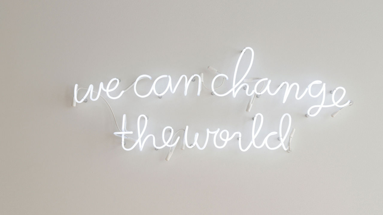 a neon sign that reads "we can change the world"