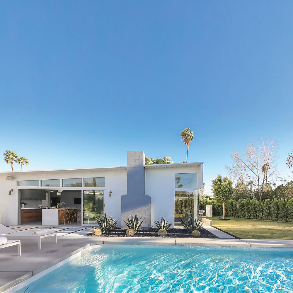 Exterior shot of a mid-century modern house with a gorgeous blue pool.