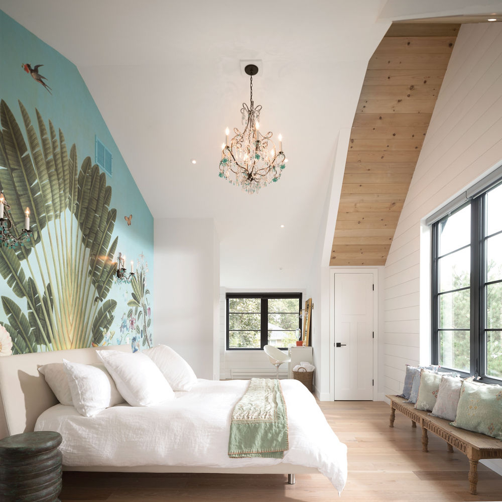 a gorgeous bedroom with white bedding, white walls, an accent blue and green mural wall, and large windows.