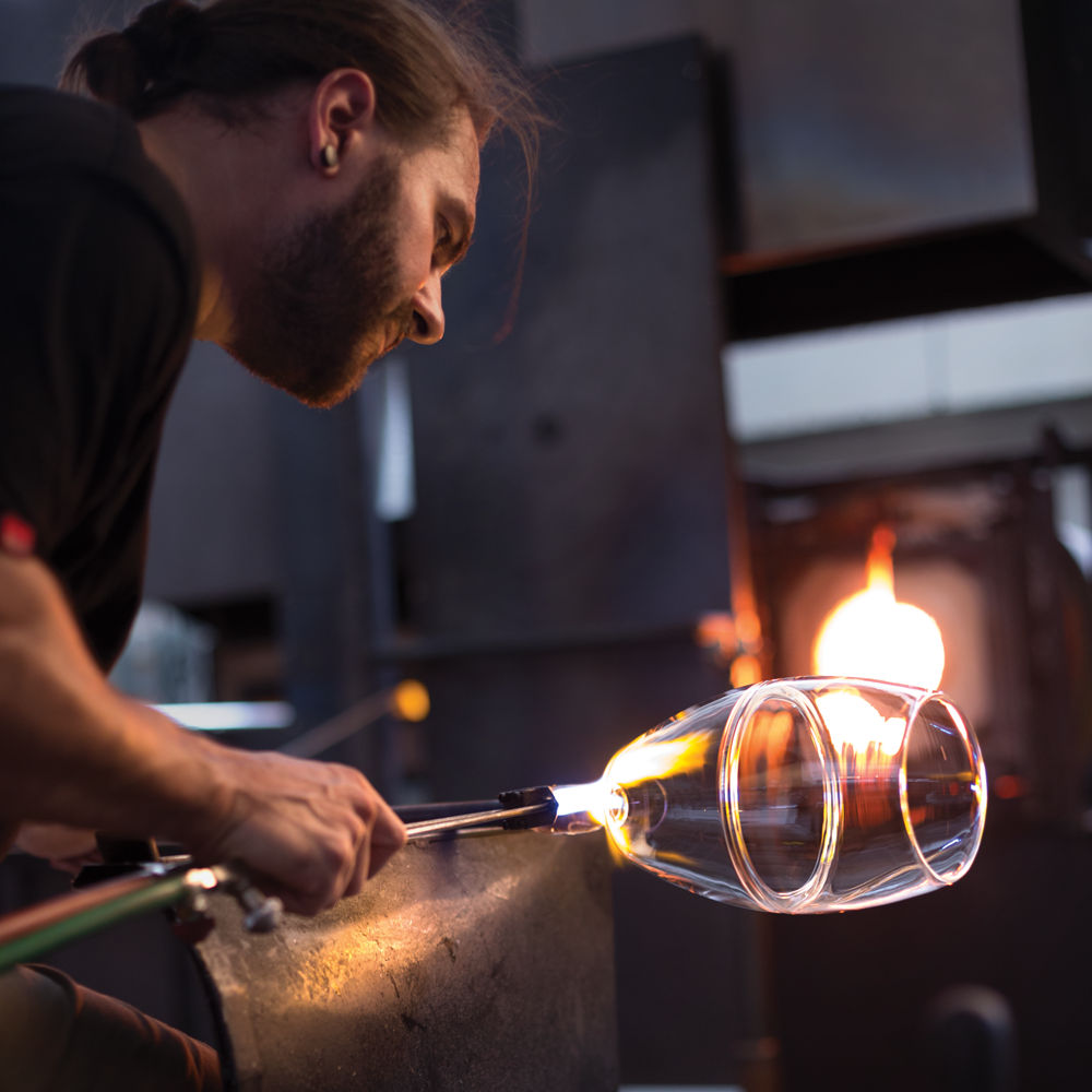 A glass blower shapes a pendant light shade..