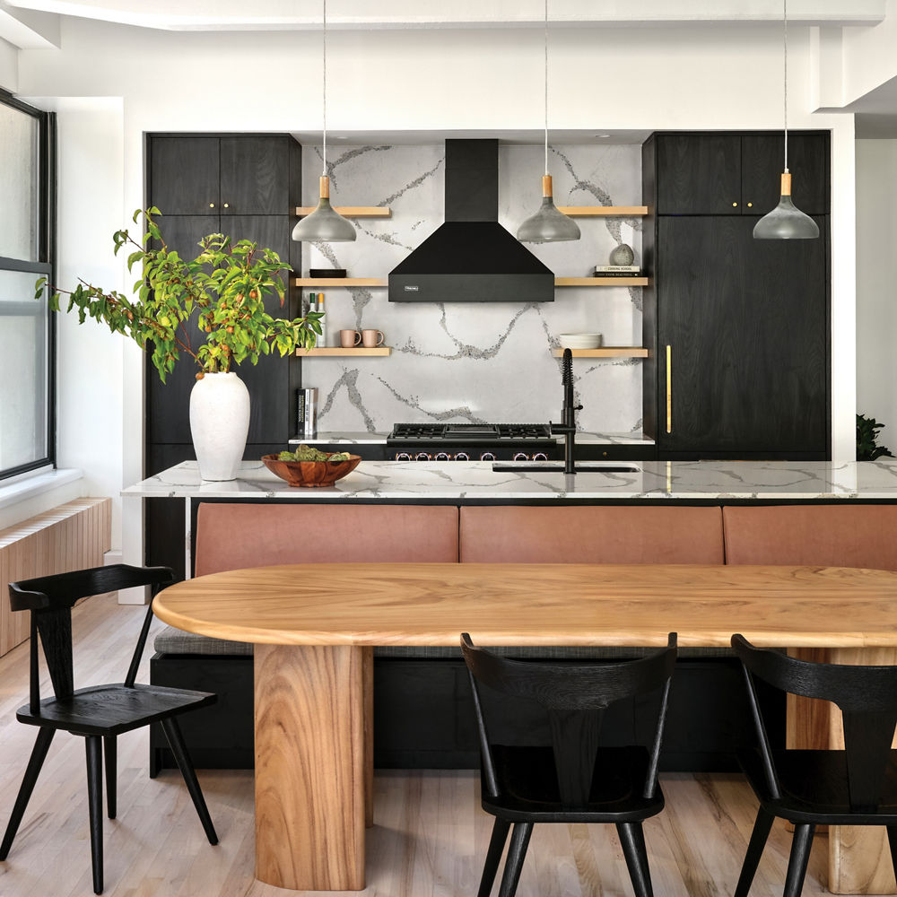 a stunning modern kitchen with matching white and gray veined quartz countertops and backsplash, black wooden cabinets, open wooden shelving, a black range and hood, and a wooden dining table with black chairs around it