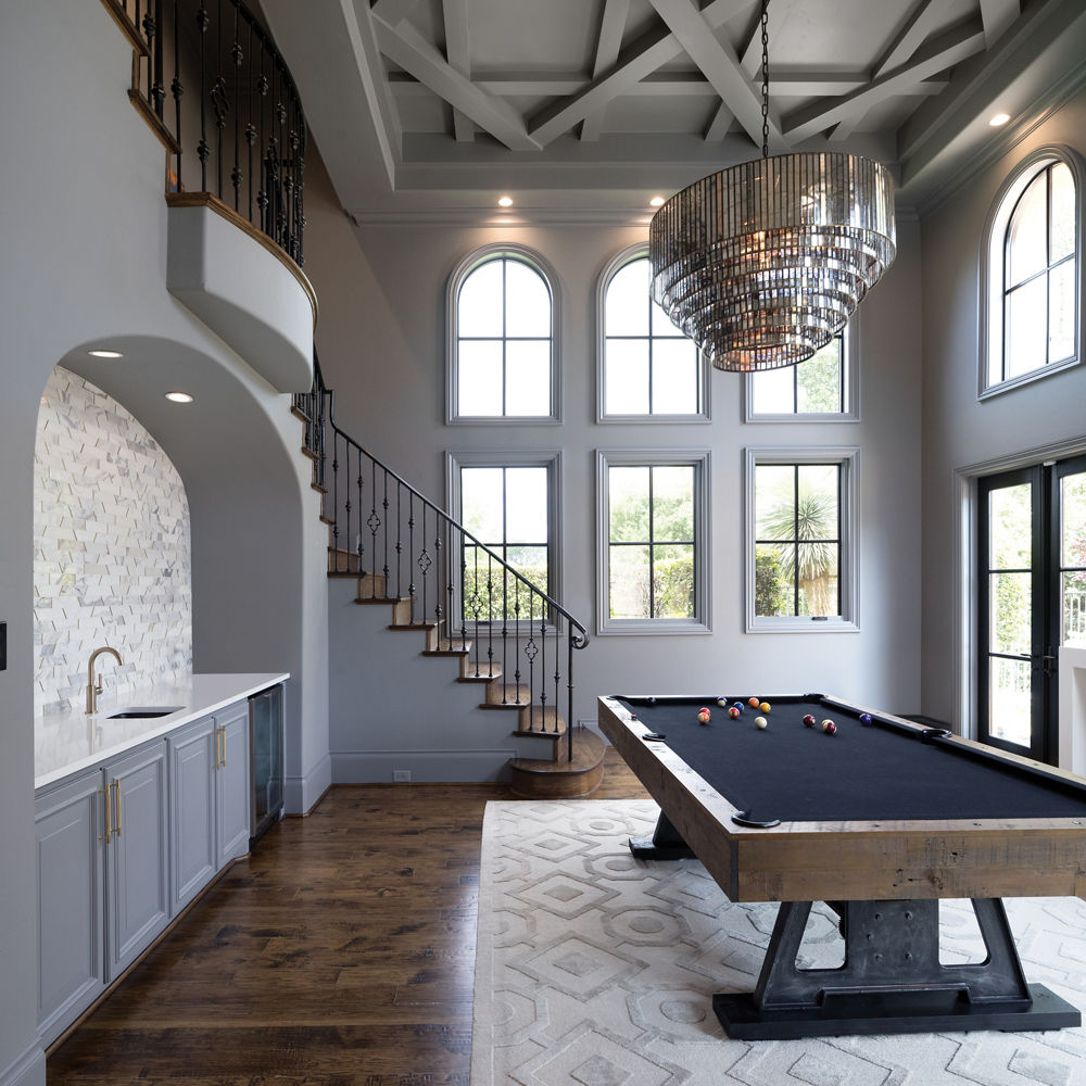 a stunning game room with a billiards table, gorgeous chandelier, wooden flooring, and a wet bar topped with white quartz.