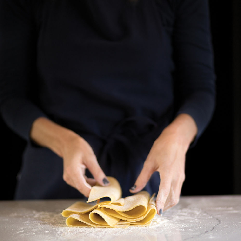 A woman folding freshly made past dough top of nonporous, maintenance-free, easy-to-clean quartz countertops. 