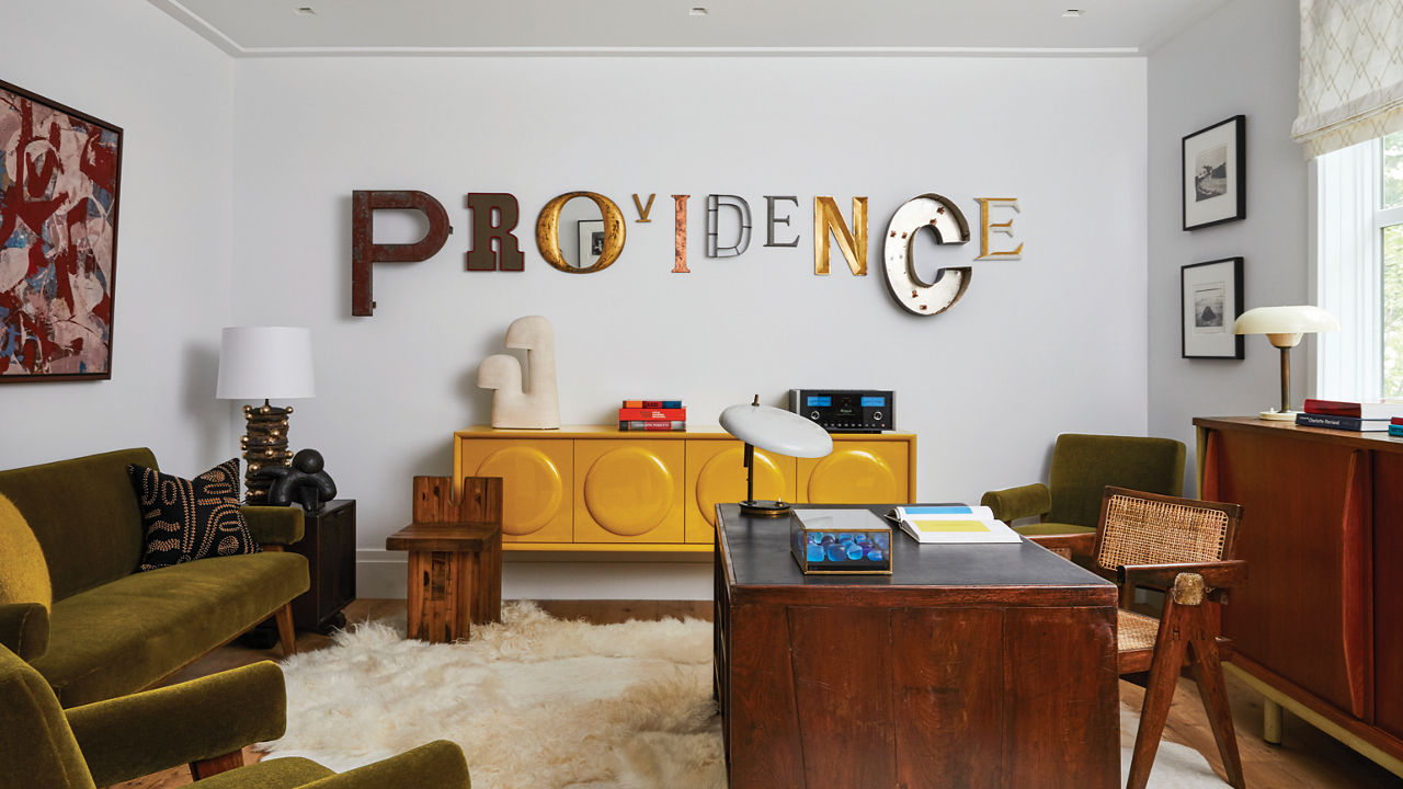 a steampunk inspired living room with tones of oak, gold, and green and letters on the wall