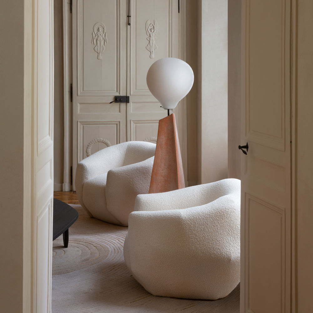 A fun and organic sitting room with white arm chairs and a unique lamp.