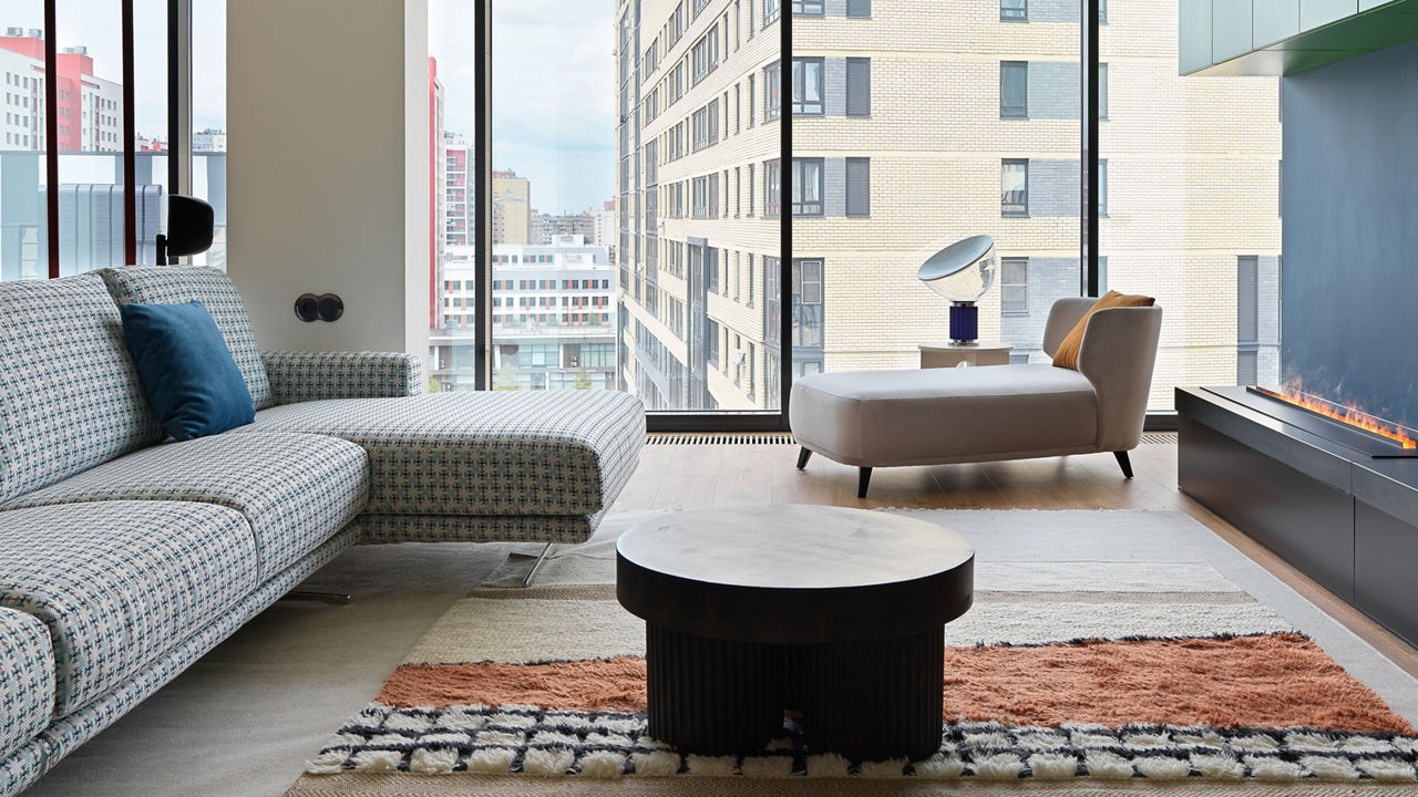 a modern living room with a sectional couch, fireplace, and a gorgeous floor-to-ceiling windows with a view of the city.