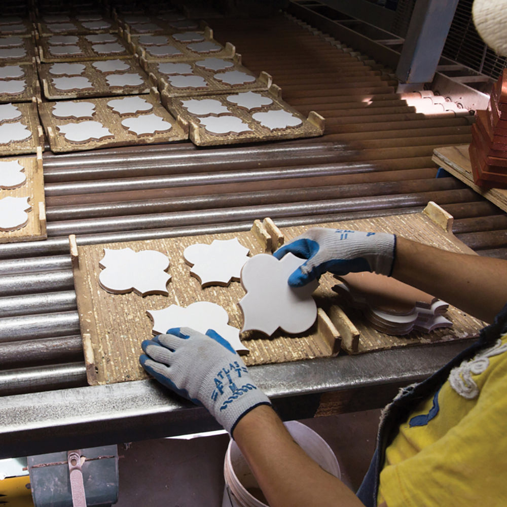 Fireclay tiles being hand cut and painted.