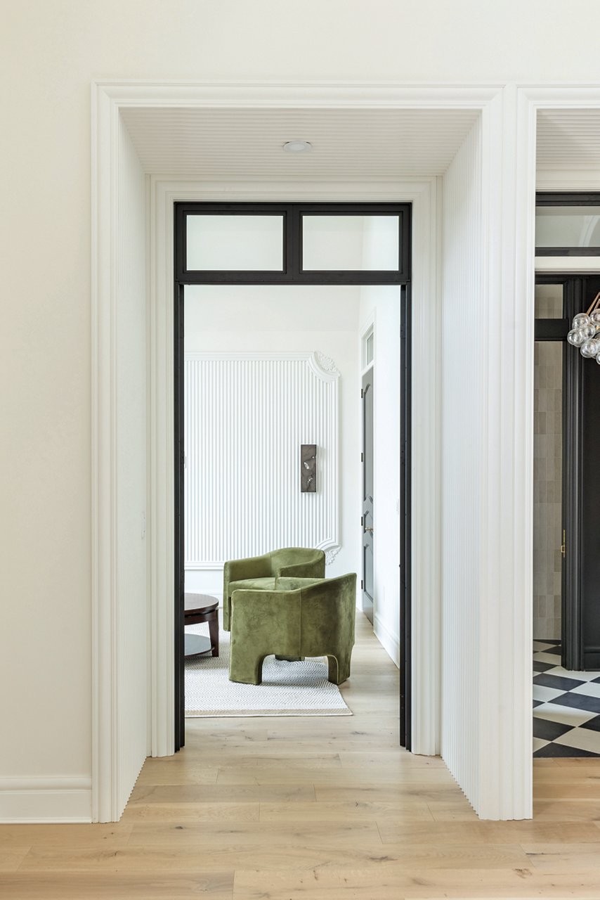 A deeply recessed doorway leading to a den with green chairs.