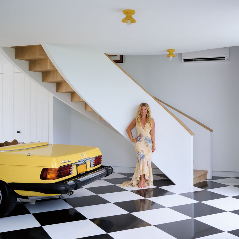 Designer Sasha Bikoff standing in her garage with a dramatic black-and-white Cambria-tiled floor.