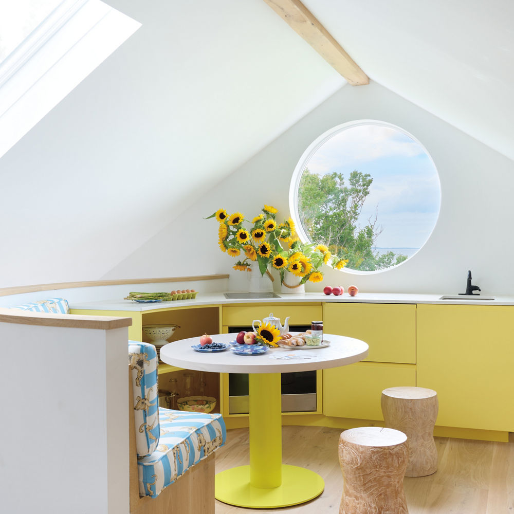 A lemon-colored kitchen with a round window.