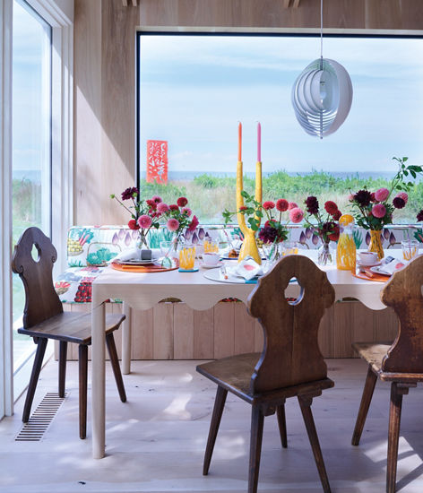 A wooden table and chairs with colorful flowers in a dining room.