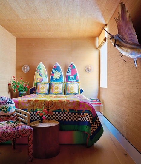 A multi-colored surfboard bed and linens in a bedroom.
