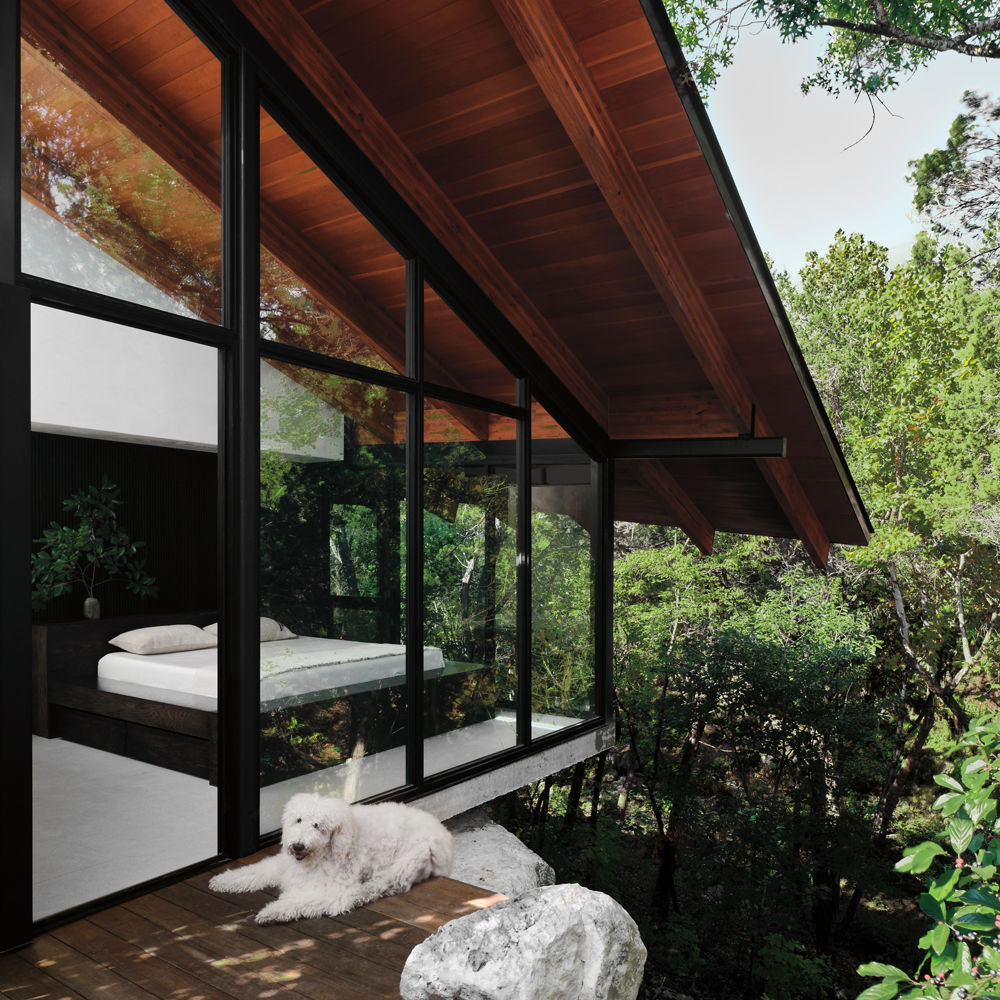 Exterior of a bedroom surrounded by windows and perched above the trees