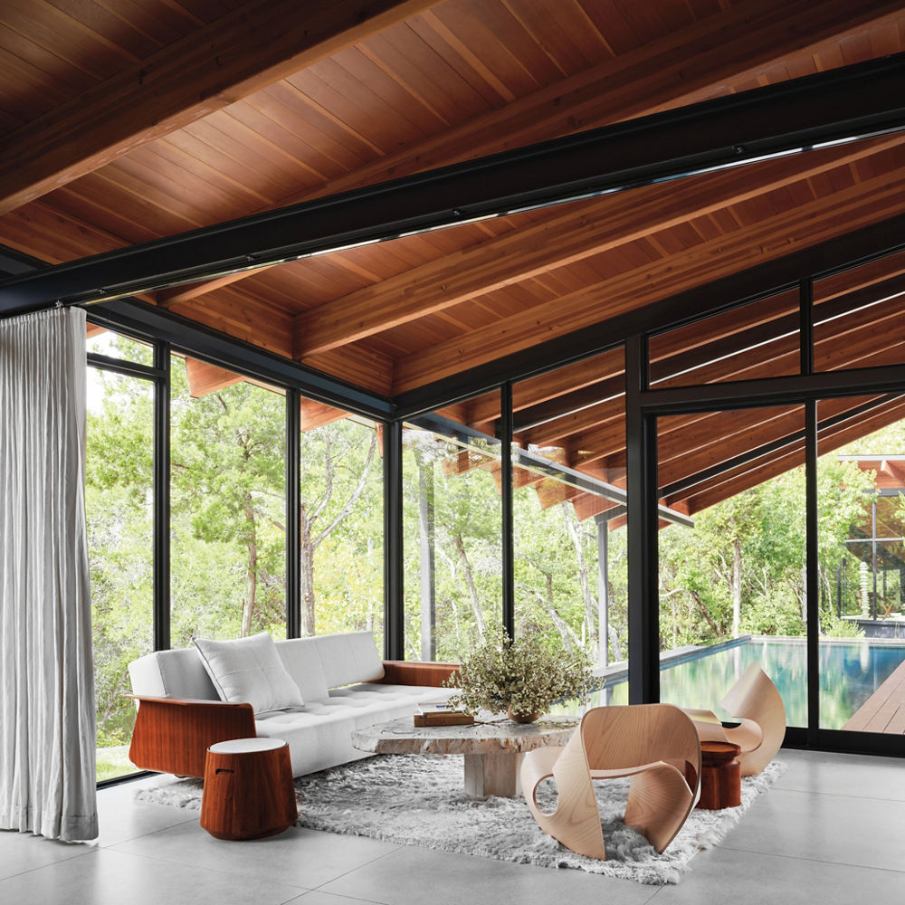 Interior of a bedroom surrounded by windows and perched above the trees