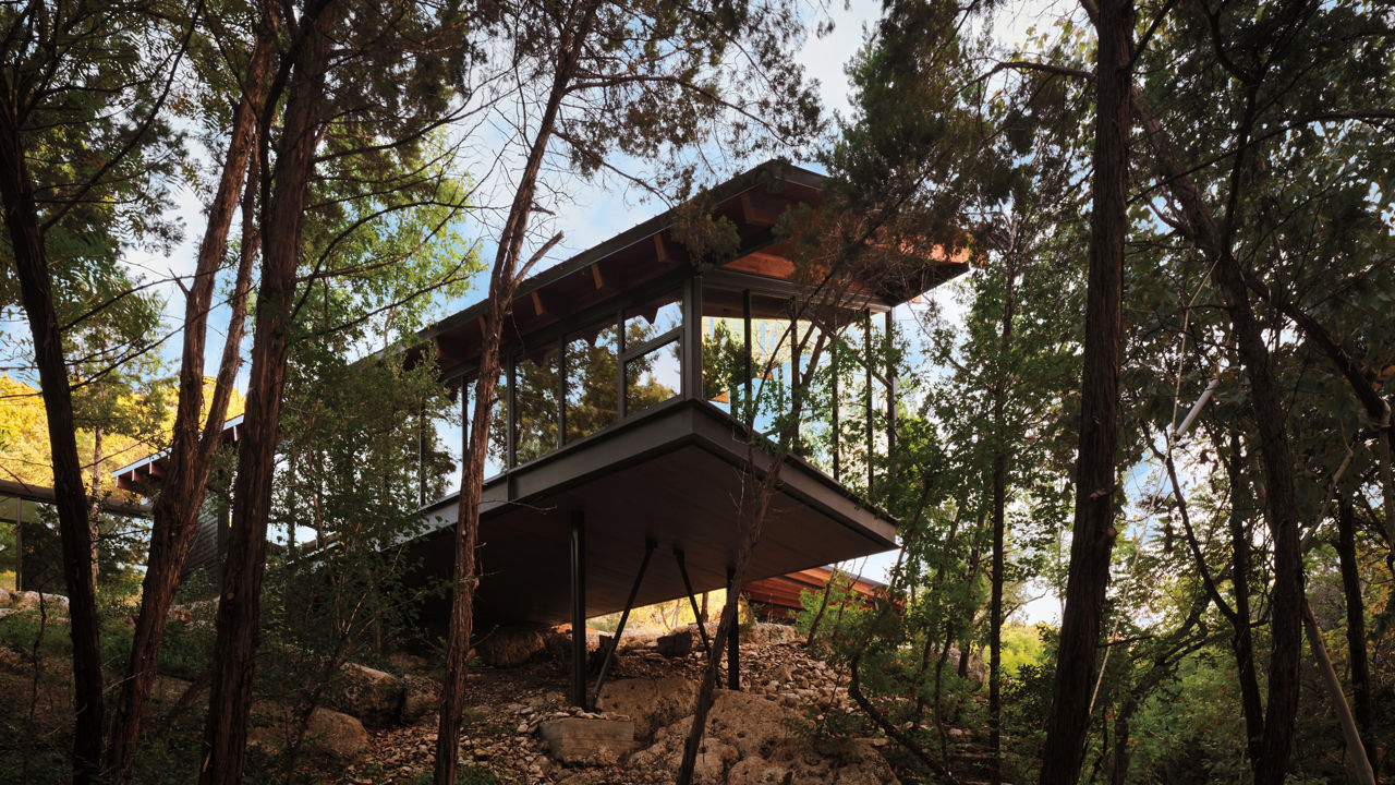 Modern home featuring floor-to-ceiling windows extending out over the trees