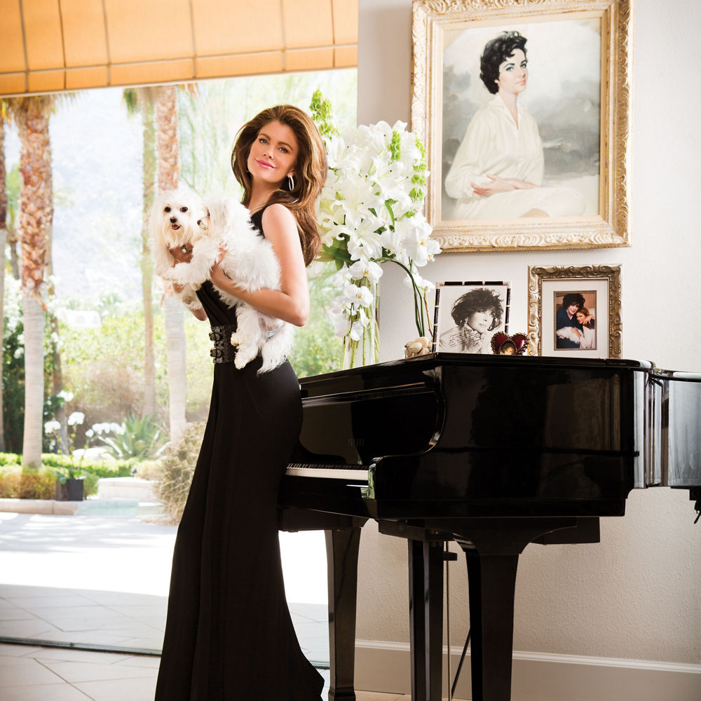 Kathy Ireland posing in a black dress with her dog.