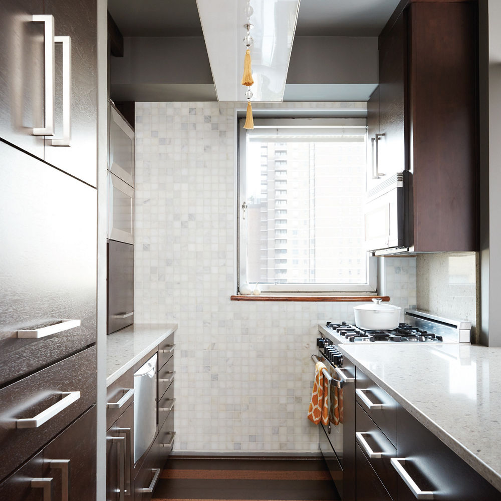 a galley kitchen with dark countertops, beige quart countertops, and stainless steal appliances