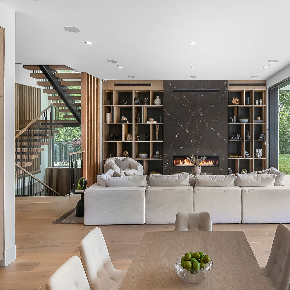 a modern living room with a white sectional sofa, black quartz fireplace, built in bookshelf, and a full-wall window.