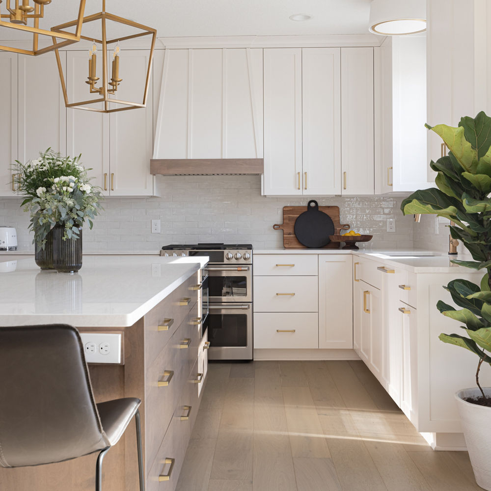 a light kitchen with white cabinets, white quartz countertops, and gold hardware.
