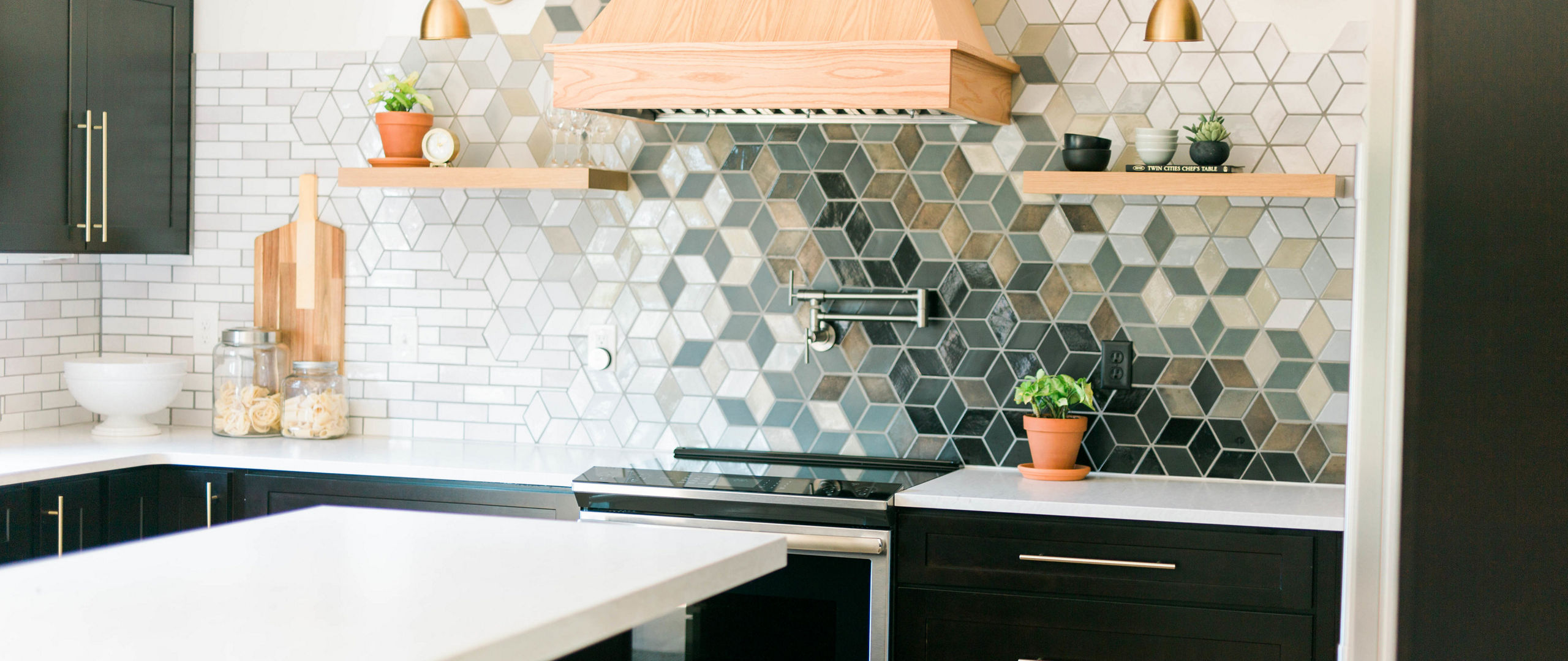 A kitchen with black cabinets, a colorful tile backsplash, gold fixtures and Delgatie Matte quartz countertops