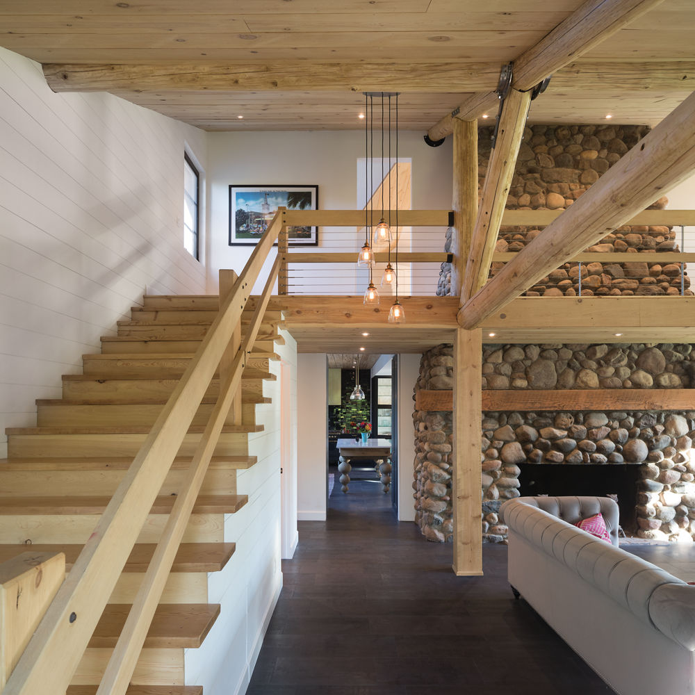 Living room with wooden staircase and white walls illuminated by hanging lights.